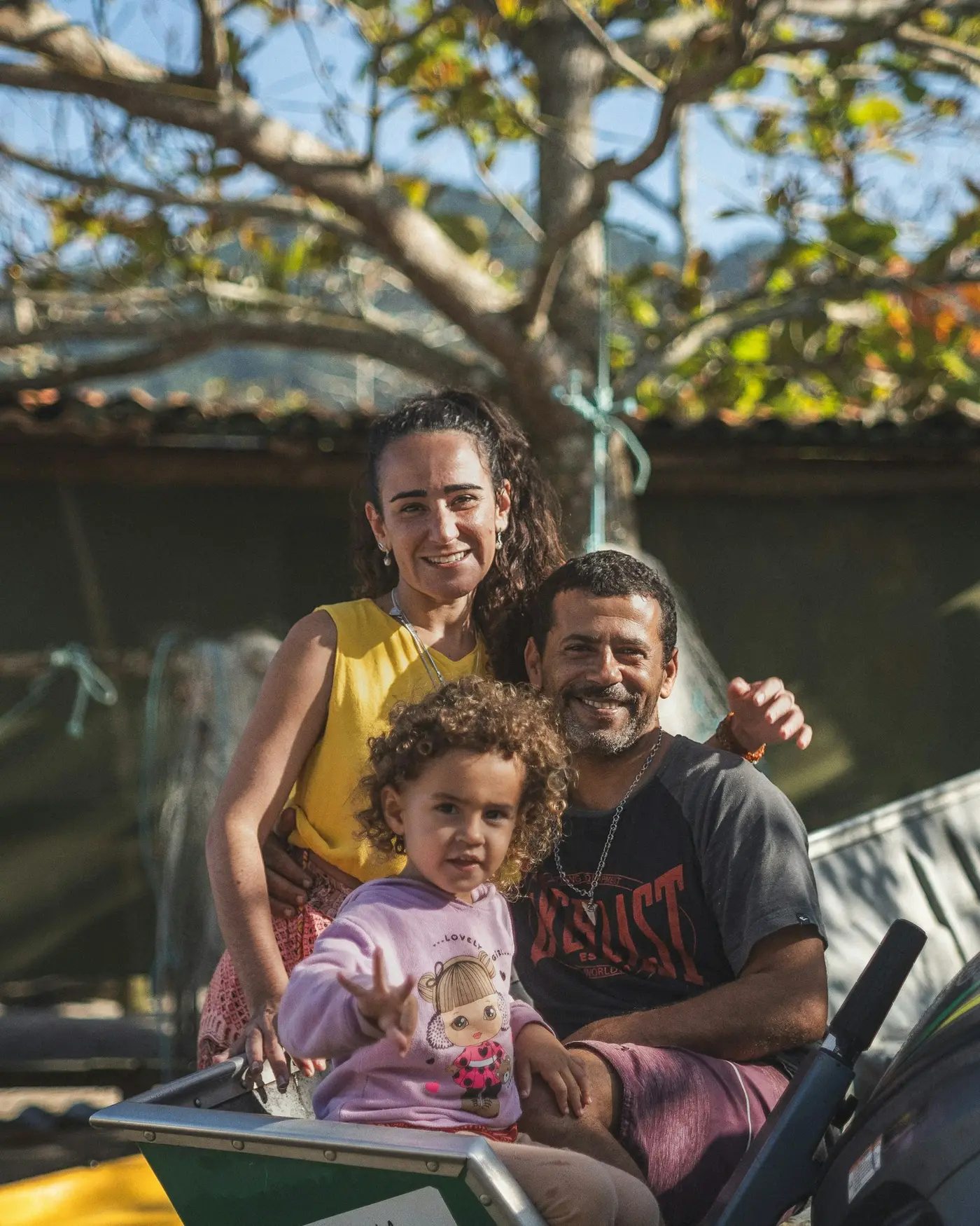 Pai, mãe e filha sorrindo juntos ao ar livre